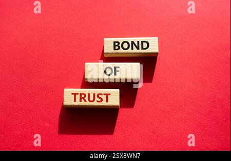 Simbolo del legame di fiducia. Blocchi di legno con parole Bond of Trust. Bellissimo sfondo rosso. Business e Bond of Trust. Copia spazio. Foto Stock