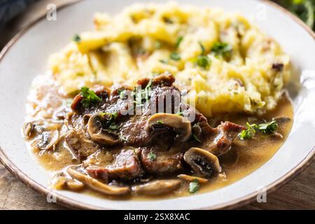 Collo di maiale arrosto con purè di patate e salsa di funghi su un piatto. Foto Stock