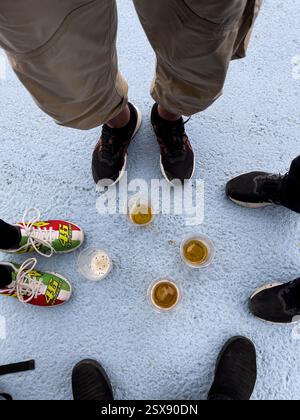 Quattro persone che bevono una birra al circuito di Misano e una indossa le scarpe Valentino Rossi Foto Stock