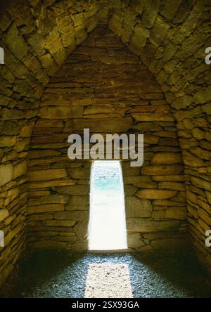 Vista interna dell'oratorio a forma di barca di Gallarus, Dingle, Co Kerry, Irlanda, che mostra la porta a testa piatta W con pietre sporgenti forate sopra. Foto Stock