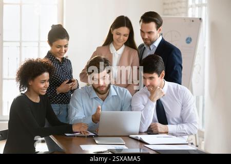 Gruppo di persone riunite intorno al notebook impegnato in una discussione Foto Stock