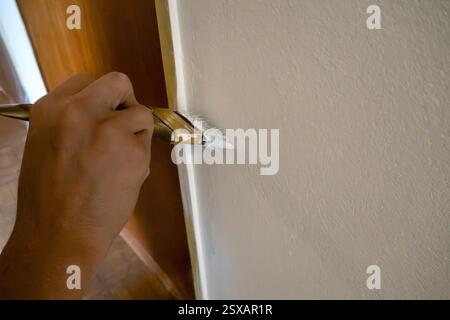 Mano che regge un pennello che dipinge un muro Foto Stock