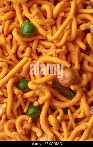 vista macro ravvicinata di patatine croccanti e speziate con mix di masala o spaghetti d'arancia fritti in profondità sullo sfondo a cornice intera, snack grovigliati Foto Stock