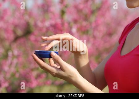 Primo piano di una donna che tiene le mani in mano la crema idratante pronta per essere applicata in un campo Foto Stock