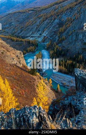 Scenario autunnale caratterizzato da un fiume tortuoso tra paesaggi rocciosi di montagna e fogliame dorato. Vibrante bellezza naturale con un'atmosfera serena. Perfetta rappresentazione della natura selvaggia e della tranquilla vista sul fiume. Foto Stock