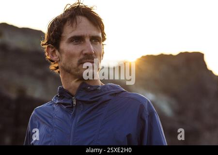 Ritratto ravvicinato dell'uomo ispanico sotto la luce del sole dorato in montagna. Foto Stock