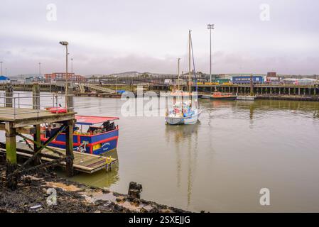 La barca a vela si mescola con le barche da pesca nel porto di Newhaven, East Sussex Foto Stock