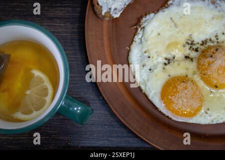 Colazione con uova dal lato soleggiato e tè al limone Foto Stock