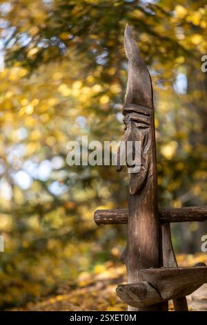 una testa scolpita in legno da un artista sconosciuto sullo sfondo di una foresta dai colori autunnali Foto Stock