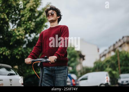 Giovane uomo che guida uno scooter elettrico in un ambiente urbano Foto Stock
