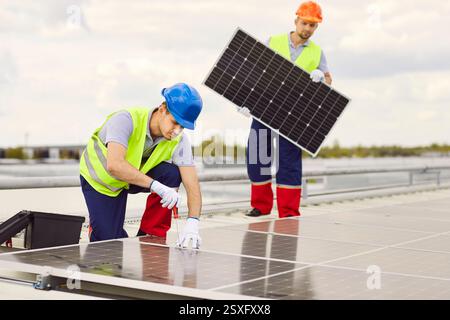 Due operai maschi che riparano o installano pannelli solari sul tetto. Foto Stock