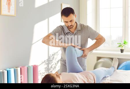 Medico o fisioterapista che allunga la gamba ferita della paziente durante la terapia fisica. Foto Stock