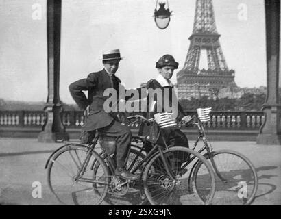 Americani o coppie americane che sventolano bandiere americane o americane cavalcando biciclette celebrano l'American Indepenence Day il 4 luglio 1918 (una settimana prima dell'Armistizio dell'11 luglio 1918) sulle rive del fiume Senna con la Torre Eiffel sullo sfondo Parigi Francia. Vintage o Historic Black and White o Monochrome Image, 4 luglio 1918. Foto Stock