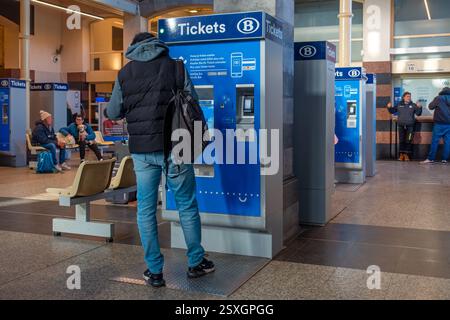 Viaggiatore / pendolare che acquista il biglietto presso il distributore automatico nella sala delle partenze della stazione ferroviaria Gent-Sint-Pieters di Gand, Fiandre orientali, Belgio Foto Stock