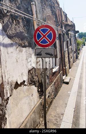 Segnale stradale urbano. Un cartello di divieto di parcheggio e zona di traino su un muro di Catania, Sicilia, Italia. Il cartello indica le rigide restrizioni di parcheggio i Foto Stock