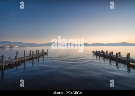 Due moli di legno o getti all'alba sul lago Massaciuccoli. Torre del Lago Puccini, Viareggio, Versilia, provincia di Lucca, regione Toscana, Italia Foto Stock