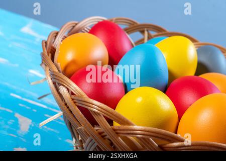 Immagina un vivace cestino pasquale pieno di morbida paglia dorata e una serie di uova colorate, ognuna un delizioso simbolo della gioiosa sacra fede Foto Stock