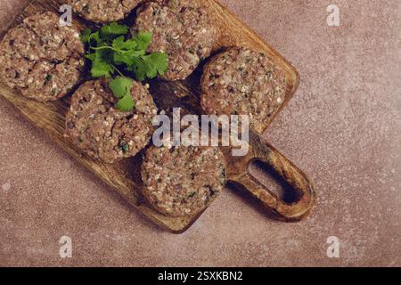 Cotolette crude, carne macinata, su un tagliere, fatti in casa, vista dall'alto, niente persone Foto Stock