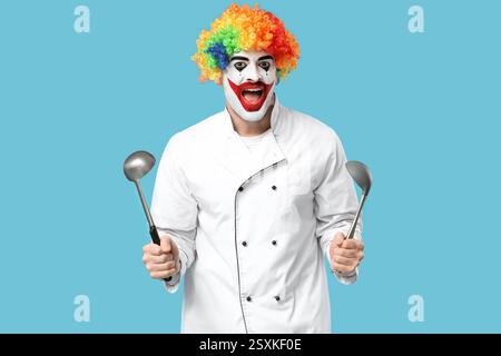 Sorprese il giovane uomo mentre cucinava il clown con mestoli su sfondo blu Foto Stock