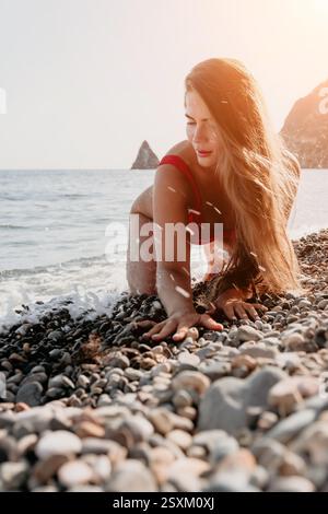Woman in Red Bikini suona in The Waves on a Pebble Beach Foto Stock