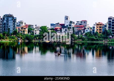 Le case di un sobborgo di Hanoi si riflettono sulla superficie del lago ho Quang Ba. Foto Stock