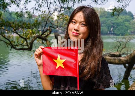 Una giovane donna con la bandiera nazionale vietnamita per celebrare il 70° anniversario della liberazione della capitale il 10 ottobre 2024. Foto Stock