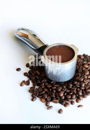 Caffè macinato nel portafiltro per espresso con chicchi di caffè su sfondo bianco. Vista dall'alto. Copia spazio. Foto Stock