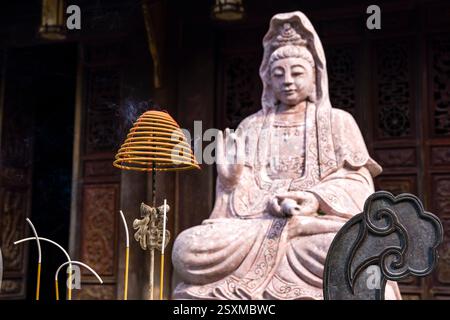 Statua del Buddha di fronte al Gian thờ Tổ Mẫu, un edificio sul sito storico del palazzo presidenziale, una spirale di incenso che brucia lentamente. Foto Stock