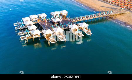 Vista aerea di un lussuoso resort sulla spiaggia con cabine private sull'acqua su un molo di legno. Foto Stock