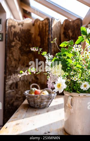 Fiori selvatici e cestino di frutta con paraventi pieghevole nel cottage Chalford Weavers nel Cotswolds, Gloucestershire, Inghilterra, Regno Unito. Foto Stock