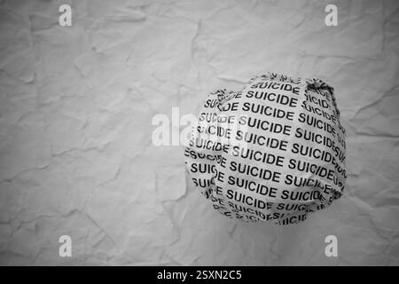 Pezzo di carta sgualcito con parole Suicide su strappato frammenti di carta bianca sullo sfondo. Foto Stock