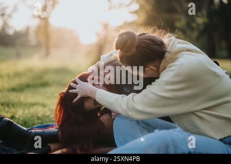 Due persone che interagiscono giocosamente in un ambiente soleggiato all'aperto Foto Stock