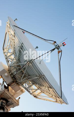 La parabola bianca è su un palo. Il piatto sta puntando verso il cielo. Il cielo è blu Foto Stock