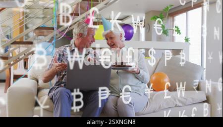 Festeggiamo il compleanno con una torta, una coppia anziana che usa il laptop sopra l'immagine dei simboli di valuta Foto Stock
