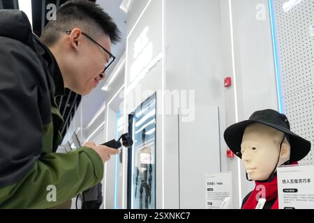 Pechino, Cina. 24 febbraio 2025. Un visitatore interagisce con il robot bionico Hobbs al Beijng World of Robots di Pechino, capitale della Cina, 24 febbraio 2025. Il Beijng World of Robots si trova nel parco industriale robotico di Yizhuang a Pechino e funge da centro espositivo completo per i robot, che mette in mostra i più recenti successi nel settore della robotica. Crediti: Ju Huanzong/Xinhua/Alamy Live News Foto Stock