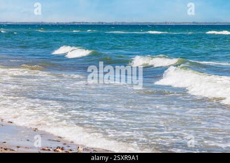Piccole onde che si infrangono sulla riva di una spiaggia sabbiosa in una giornata di sole sul mar baltico in germania. Foto Stock