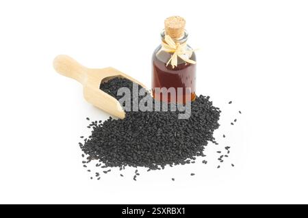 Bottiglia in vetro di olio essenziale di semi di cumino nero , Nigella Sativa in cucchiaio isolato su fondo bianco Foto Stock