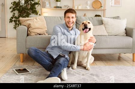 Giovane uomo felice con cane seduto sul pavimento Foto Stock