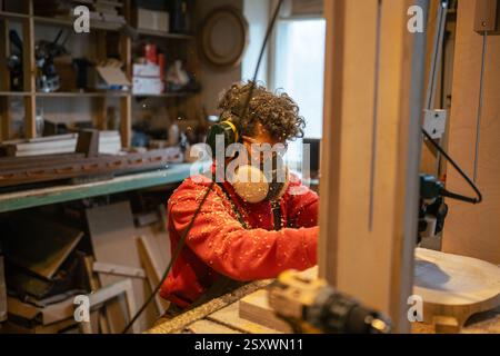 Officina di falegnameria artigiano che lavora con maestri. L'utensile per fresatura manuale del legno tiene fermo il processo di controllo dell'utensile Foto Stock