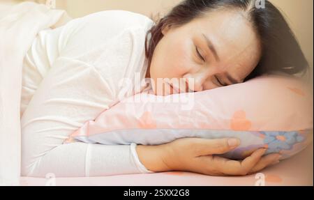 Bella donna adulta asiatica con coperta che dorme sul letto a casa, copia spazio. concetto inalterato, di stile di vita e di relax. Foto Stock