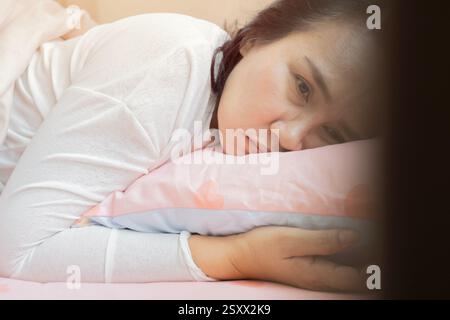 Vista laterale donna infelice sensazione di stress o mal di testa dopo un improvviso risveglio al mattino presto, giovane donna stanca che soffre di insonnia o migrai Foto Stock