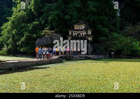 Un gruppo di turisti cammina fino all'ingresso del complesso del tempio Bich Äáng, costruito nel 1428, vicino al villaggio di Tam Coc. Ninh Binh Ninh Bin Province vie Foto Stock