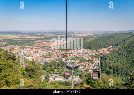 Thale, Germania – 27 agosto 2024: I turisti in sella alla seggiovia che collega Thale con la falesia di granito alta 403 metri Rosstrappe godono di una splendida vista Foto Stock