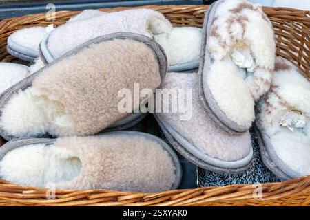 Pantofole calde in lana di pecora - comode pantofole in pelliccia in un cestino in vimini, perfette per la stagione fredda. Foto Stock