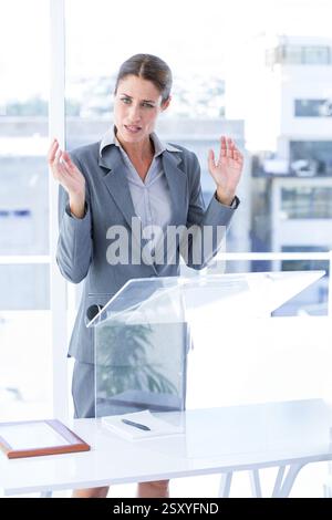 Presentazione, donna d'affari in piedi sul podio nella moderna sala riunioni Foto Stock