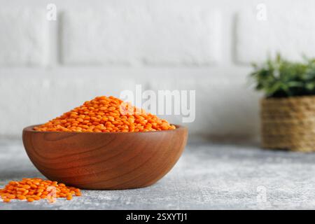 Lenticchie rosse in una ciotola di legno e un mucchio sparso sul bancone della cucina Foto Stock