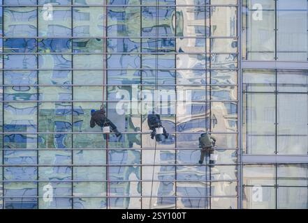 Almaty, Kazakistan - 21 febbraio 2025: Tre scalatori puliscono la facciata di vetro di un edificio. Azienda di pulizie Foto Stock