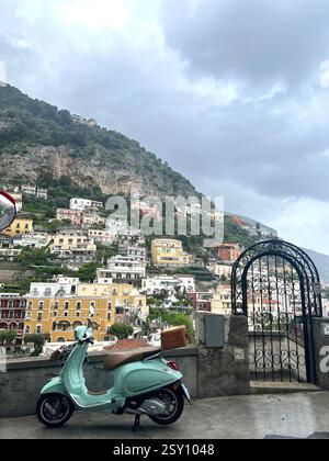 Vespa verde menta con vista sull'iconica collina di Positano Foto Stock
