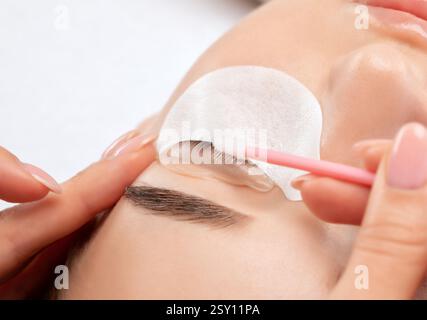 Il make-up artist esegue la procedura di laminazione e tintura delle ciglia a una bella donna in un salone di bellezza. Estensioni delle ciglia. Sollevamento ciglia Foto Stock