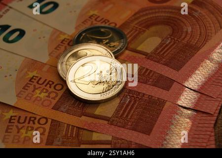 Nuove e brillanti monete da 2 euro su banconote da 10 euro. Valuta della zona euro. Foto Stock